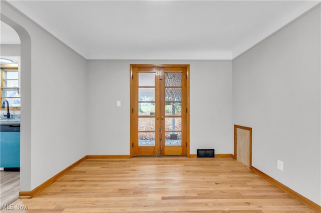 empty room with french doors, light hardwood / wood-style flooring, and sink