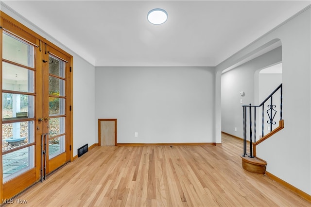 empty room with french doors and light hardwood / wood-style flooring