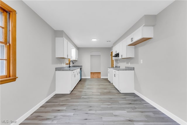 kitchen with white cabinetry, sink, light hardwood / wood-style floors, and light stone counters