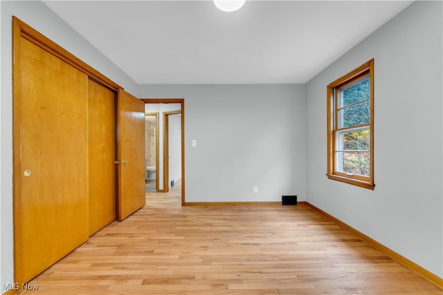 unfurnished bedroom with light wood-type flooring and a closet