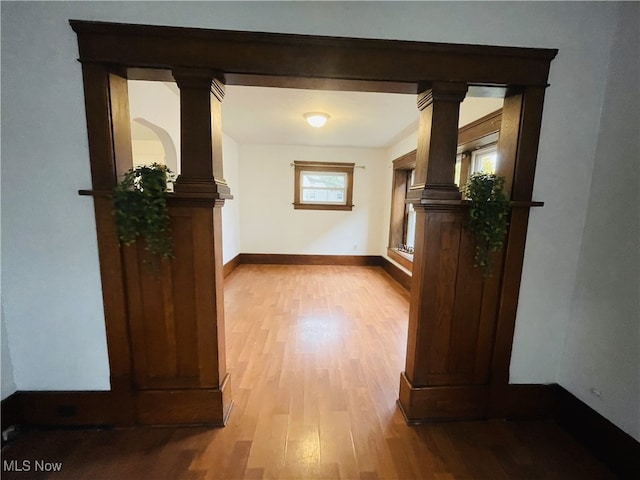 hallway with light wood-type flooring and decorative columns