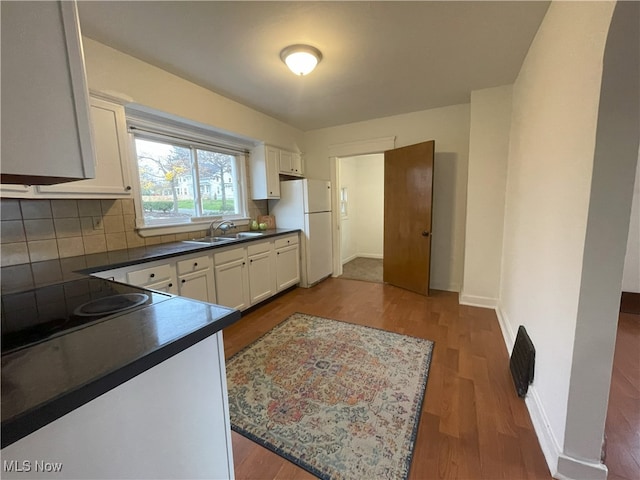 kitchen with white refrigerator, sink, white cabinetry, cooktop, and wood-type flooring