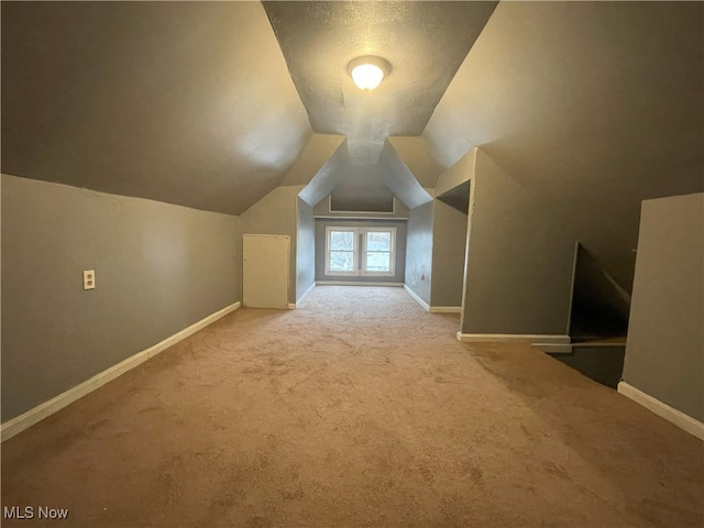 additional living space featuring a textured ceiling, carpet floors, and vaulted ceiling