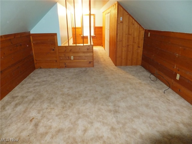 bonus room featuring wooden walls, light colored carpet, and lofted ceiling