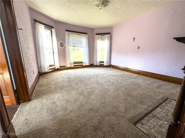 carpeted empty room with a textured ceiling