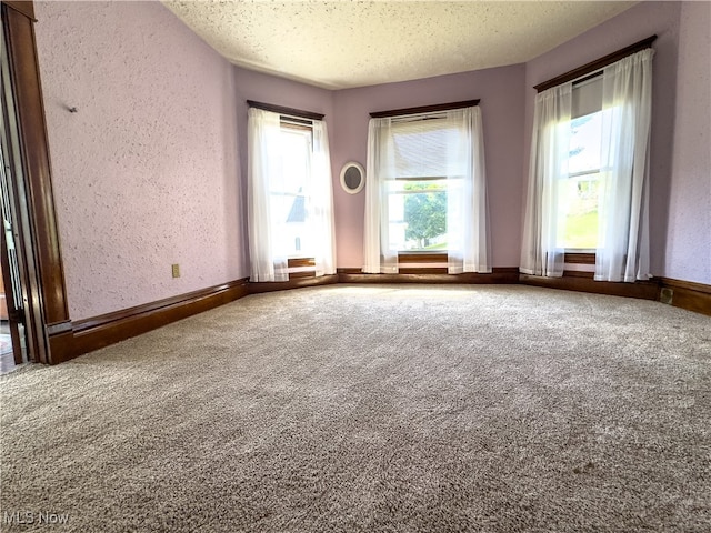 carpeted empty room with a textured ceiling