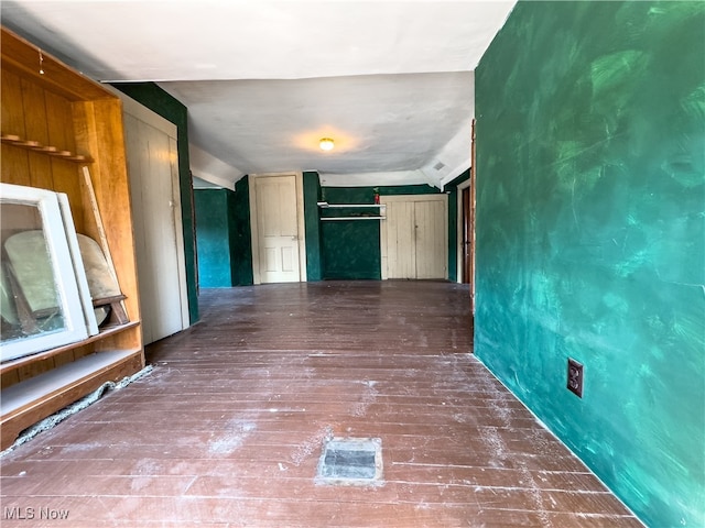 corridor with wood-type flooring and lofted ceiling