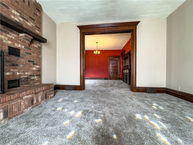 unfurnished living room with carpet, a fireplace, and a notable chandelier