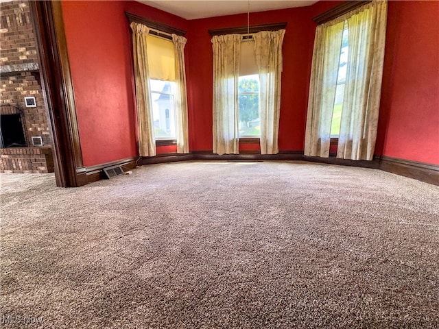 carpeted spare room with a fireplace