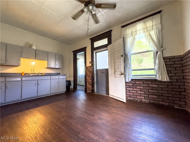 kitchen with gray cabinets, sink, brick wall, and dark hardwood / wood-style floors