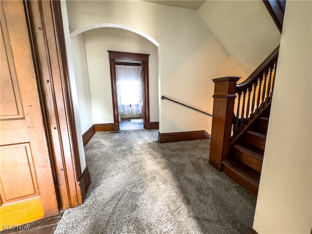 hallway featuring dark colored carpet and lofted ceiling