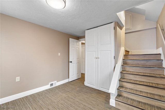 stairway featuring a textured ceiling