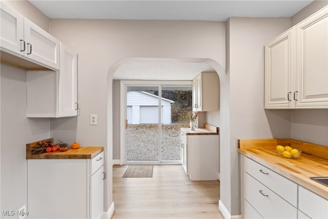 kitchen with butcher block countertops, white cabinetry, and light hardwood / wood-style flooring