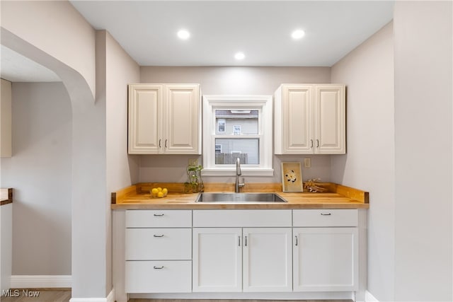 kitchen with white cabinets, sink, and wooden counters