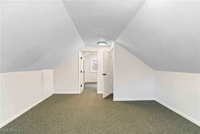 bonus room with dark carpet and lofted ceiling