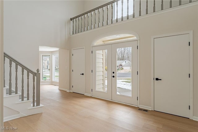 entryway featuring a towering ceiling and light hardwood / wood-style flooring