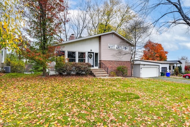 view of front of house with a garage, central AC unit, and a front yard