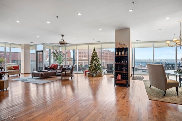 living room featuring expansive windows, light hardwood / wood-style floors, and ceiling fan with notable chandelier