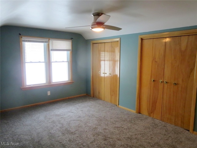 unfurnished bedroom with carpet flooring, multiple closets, lofted ceiling, and ceiling fan