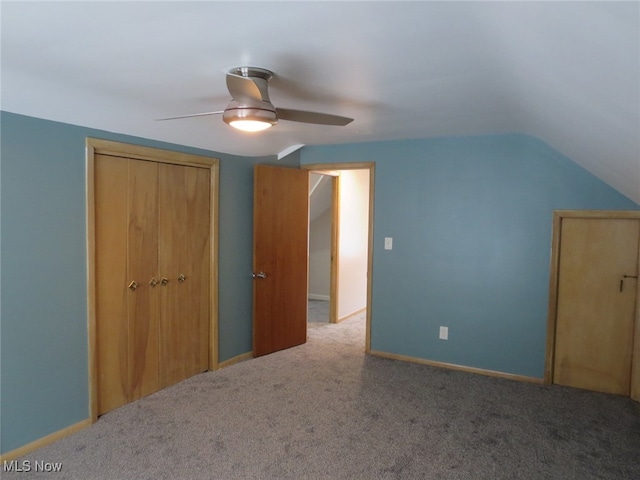 unfurnished bedroom with ceiling fan, a closet, carpet floors, and lofted ceiling