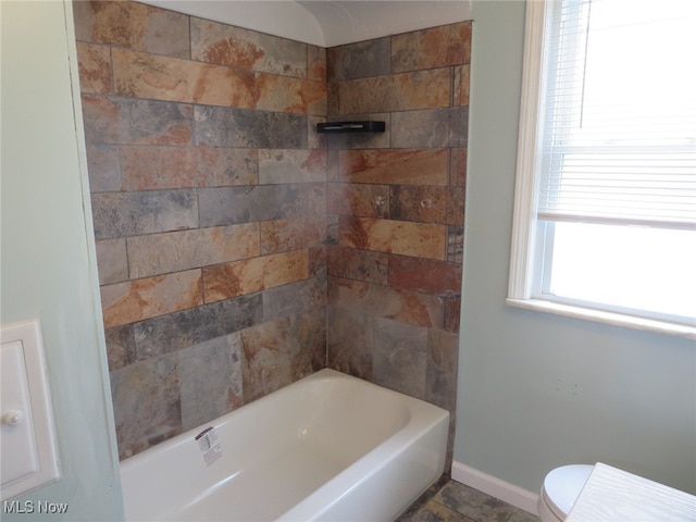 bathroom with toilet and tiled shower / bath