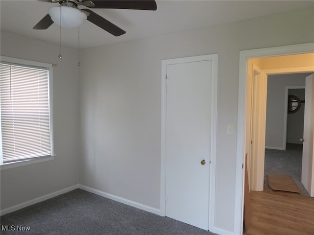 unfurnished bedroom featuring dark hardwood / wood-style floors, multiple windows, and ceiling fan