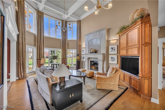 living room featuring coffered ceiling, a large fireplace, light hardwood / wood-style flooring, a notable chandelier, and beamed ceiling