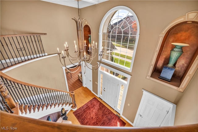 foyer with a towering ceiling, hardwood / wood-style flooring, and an inviting chandelier