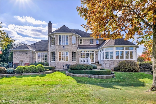 back of house featuring a yard and a sunroom