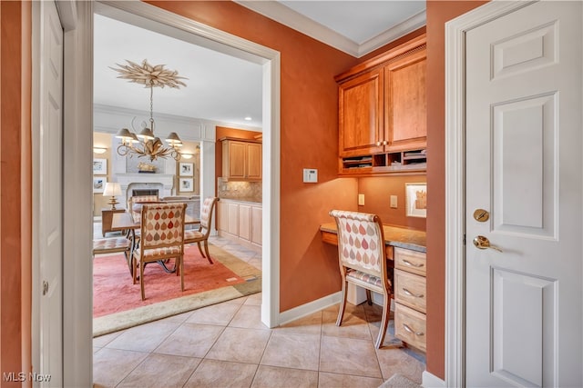 office space with a chandelier, light tile patterned floors, built in desk, and ornamental molding