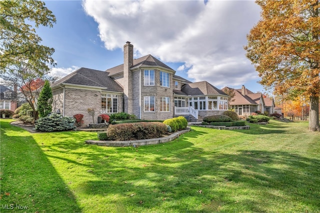 rear view of house featuring a sunroom and a yard