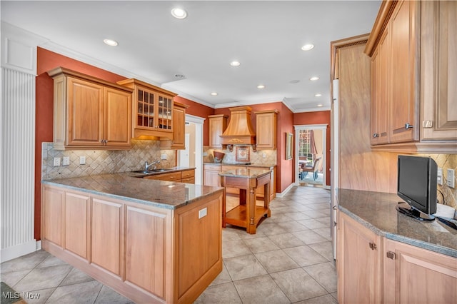 kitchen with backsplash, custom exhaust hood, sink, light tile patterned floors, and dark stone countertops