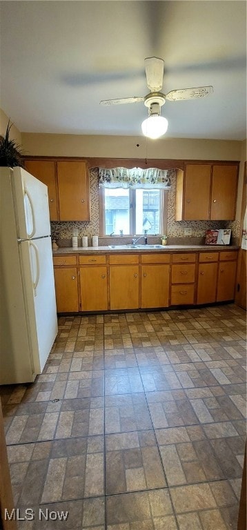 kitchen with decorative backsplash, white fridge, ceiling fan, and sink