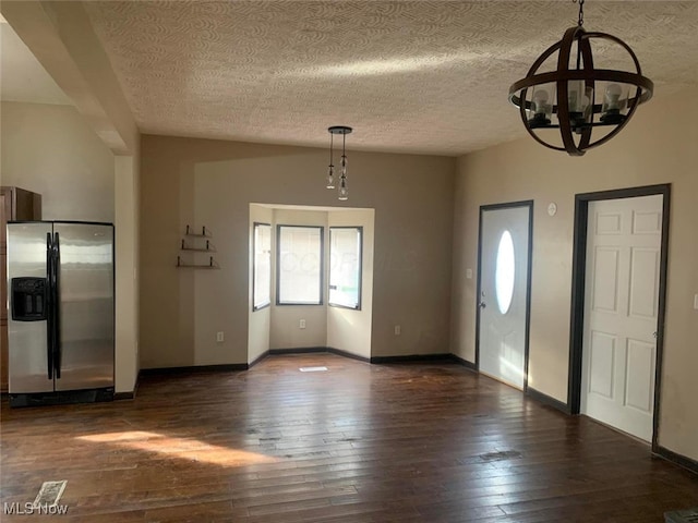 entryway featuring a textured ceiling, dark hardwood / wood-style floors, and an inviting chandelier