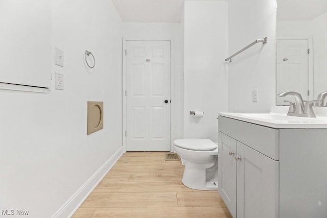 bathroom with wood-type flooring, vanity, and toilet