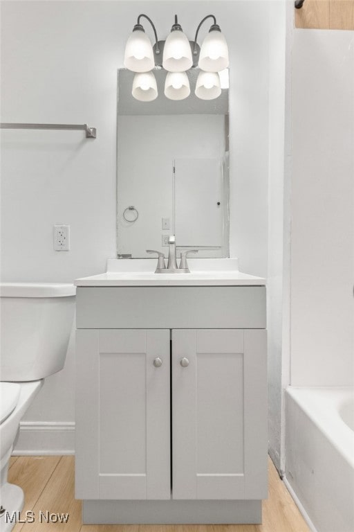 full bathroom featuring hardwood / wood-style floors, vanity, toilet, and shower / bathtub combination