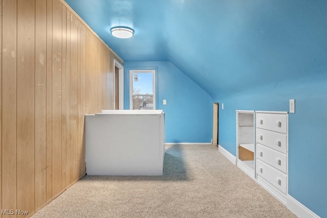 additional living space with light carpet, wooden walls, and lofted ceiling