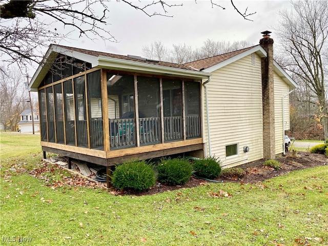 view of side of home featuring a sunroom and a yard