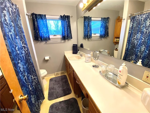 bathroom featuring plenty of natural light, toilet, and vanity