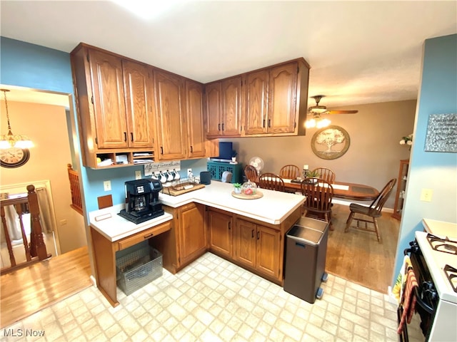 kitchen with white range with gas stovetop, ceiling fan with notable chandelier, and light hardwood / wood-style floors