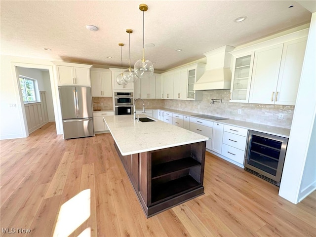 kitchen featuring white cabinetry, sink, beverage cooler, premium range hood, and appliances with stainless steel finishes