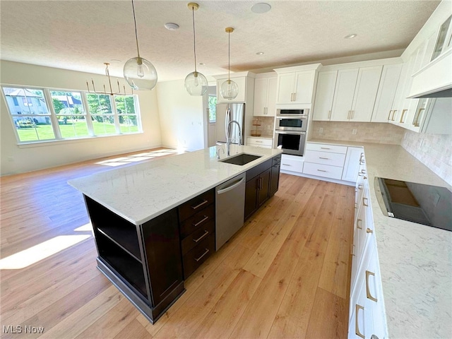 kitchen featuring decorative backsplash, stainless steel appliances, light hardwood / wood-style flooring, and an island with sink