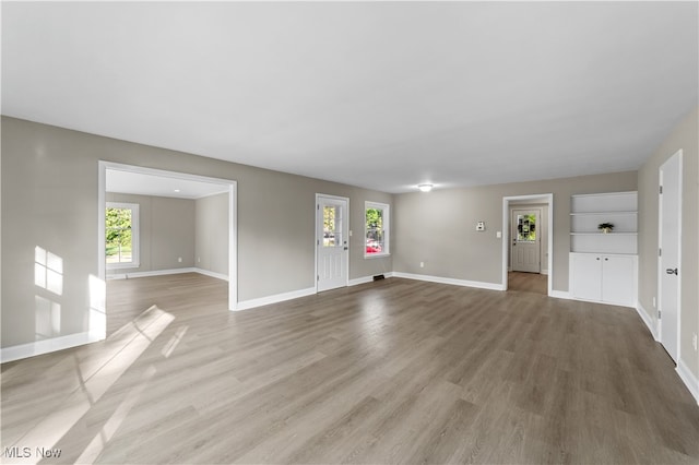 unfurnished living room with hardwood / wood-style flooring and a healthy amount of sunlight