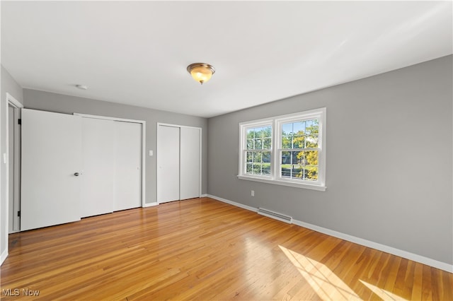 unfurnished bedroom featuring light hardwood / wood-style floors and multiple closets