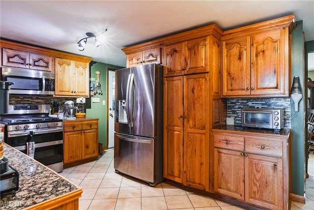 kitchen with backsplash, light tile patterned flooring, and appliances with stainless steel finishes