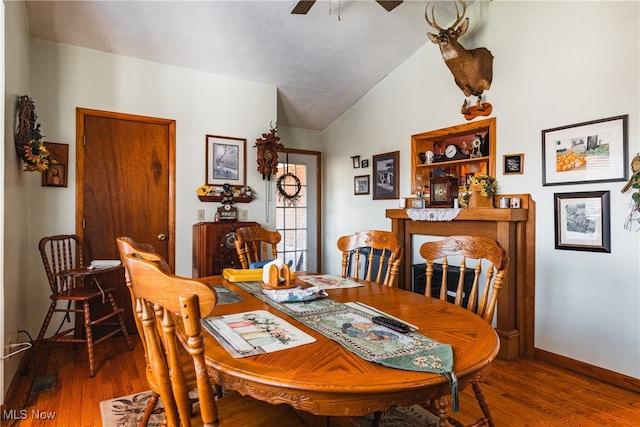 dining space featuring lofted ceiling, ceiling fan, wood-type flooring, and a textured ceiling