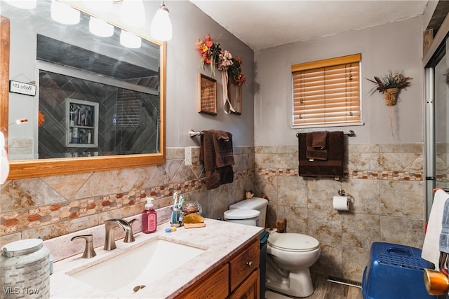 bathroom featuring vanity, toilet, and tile walls