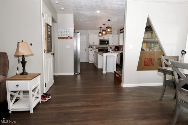 kitchen featuring pendant lighting, white cabinets, a textured ceiling, appliances with stainless steel finishes, and dark hardwood / wood-style flooring