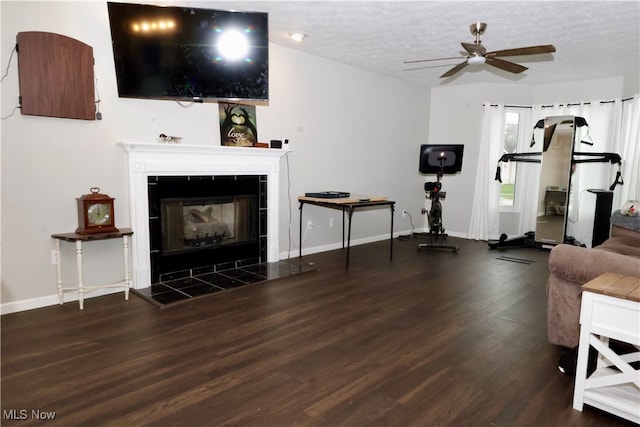 living room featuring a textured ceiling, a fireplace, ceiling fan, and dark wood-type flooring