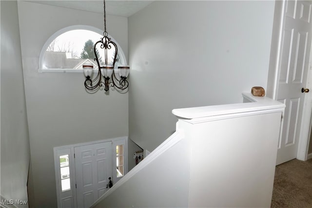 carpeted foyer entrance featuring a notable chandelier